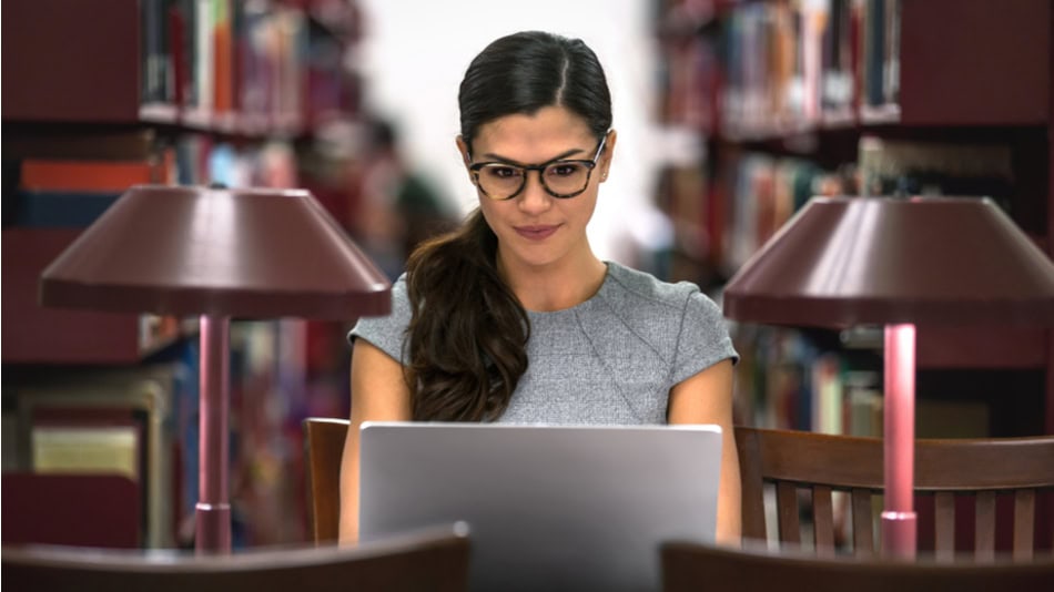 Una mujer latina estudiando en la biblioteca con portátil