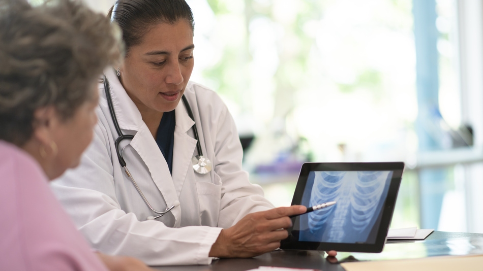 Médico con una paciente enseñándole una radiografía como parte de su estudio de gerontología